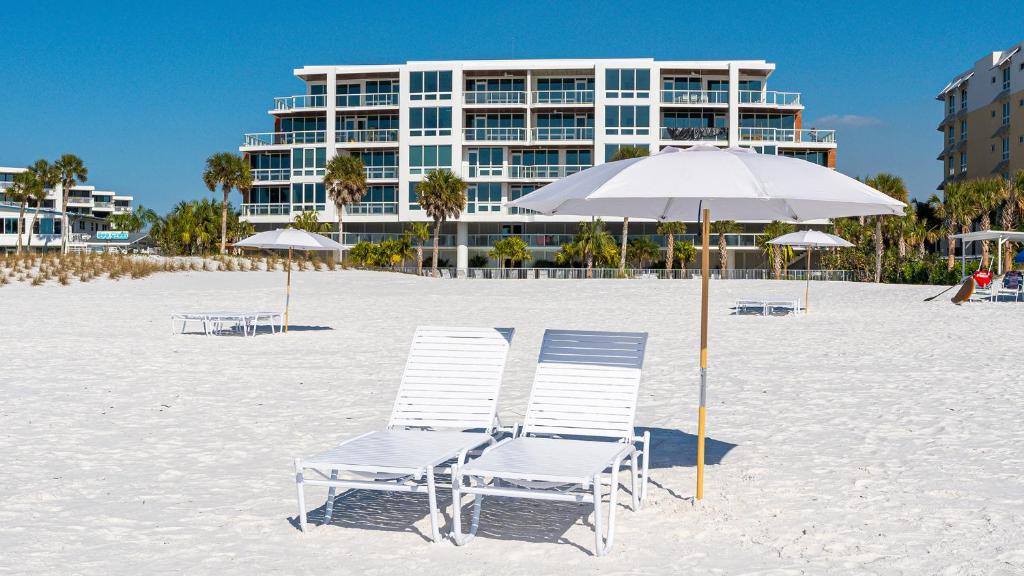two beach chairs and an umbrella on the beach at Ten35 Seaside Rentals in Sarasota