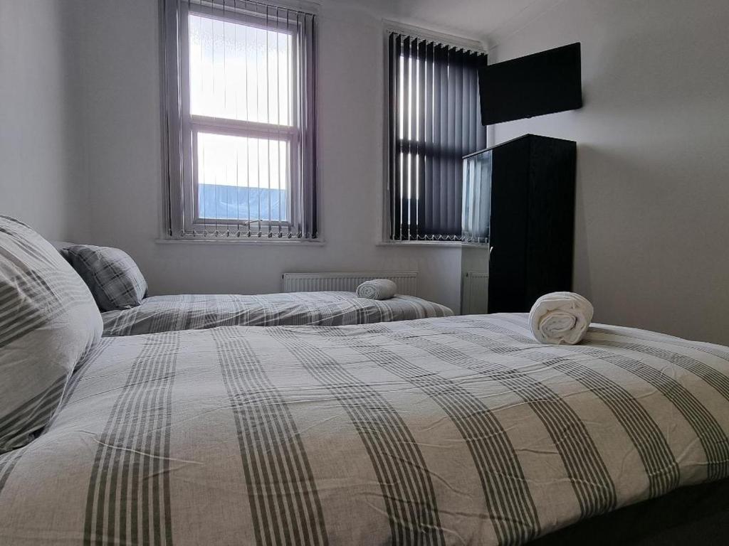 a bedroom with two beds and two windows at Portside Liverpool in Liverpool