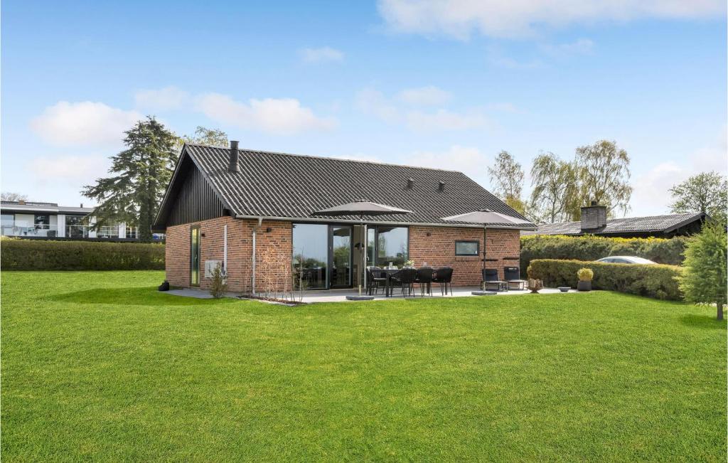a brick house with a black roof on a lawn at Awesome Home In lsted With Wifi in Ølsted