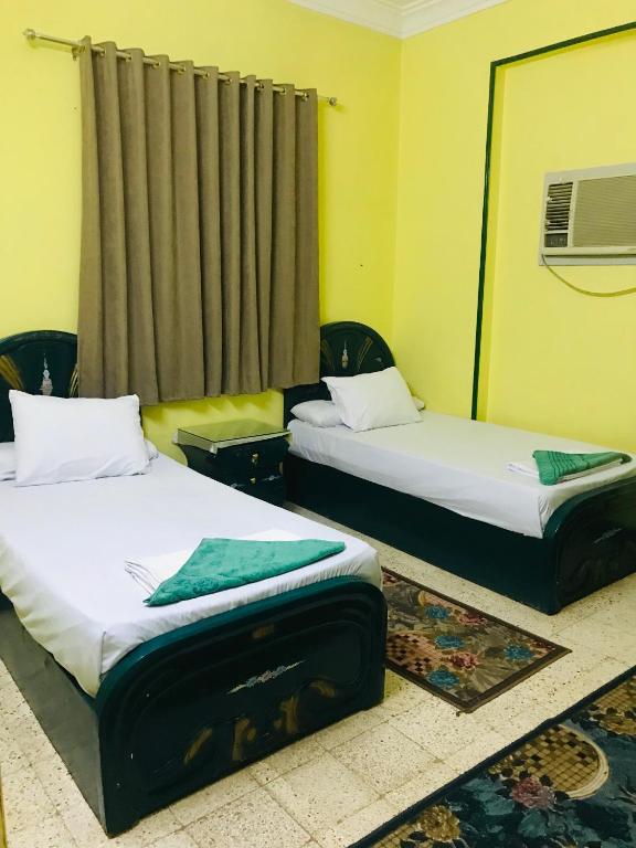 two beds in a room with yellow walls at Gamal Robob Nubian Guest House in Aswan