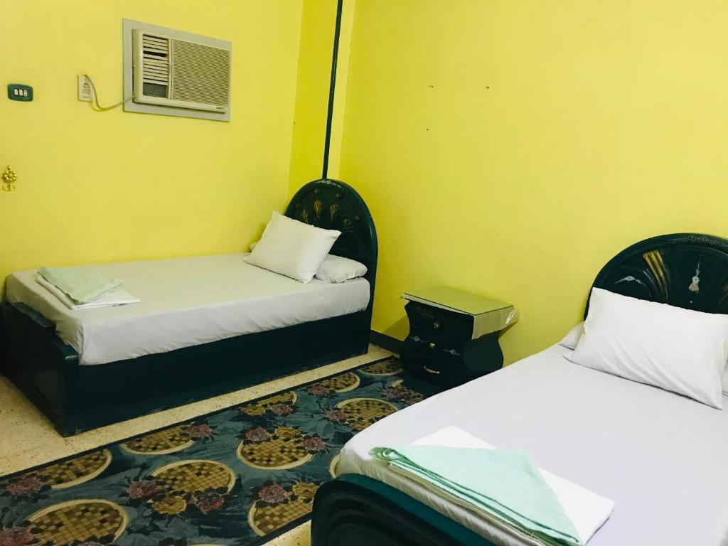 two beds in a room with yellow walls at Gamal Robob Nubian Guest House in Aswan