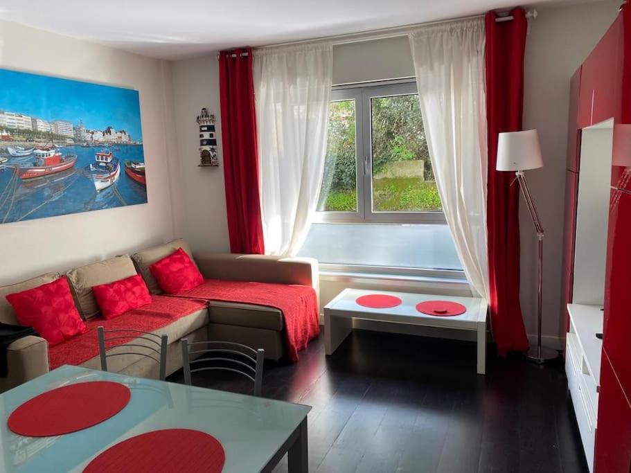 un soggiorno con divano rosso e finestra di Apartamento de playa familiar, piscina y garaje. a Ares