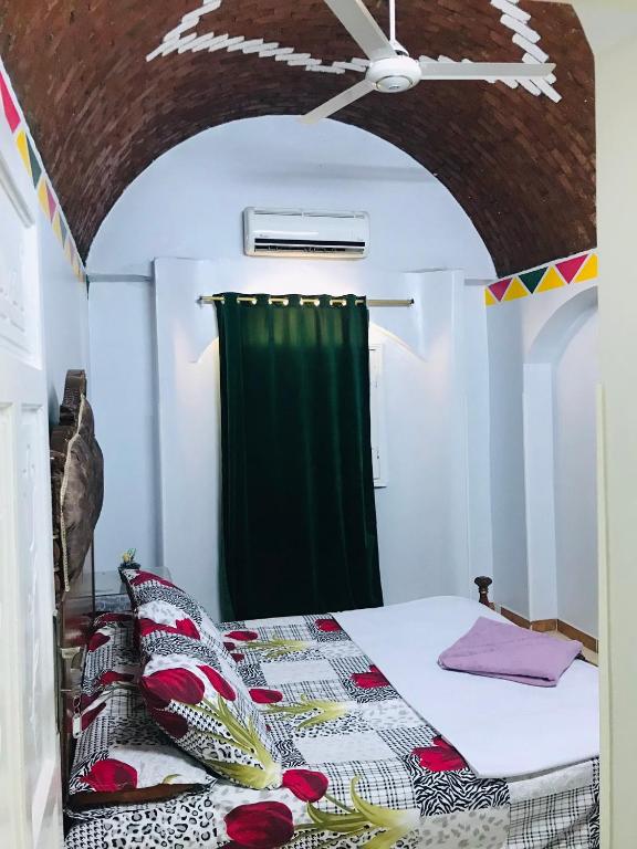 a bedroom with a bed with a green curtain at Gamal Robob Nubian Guest House in Aswan