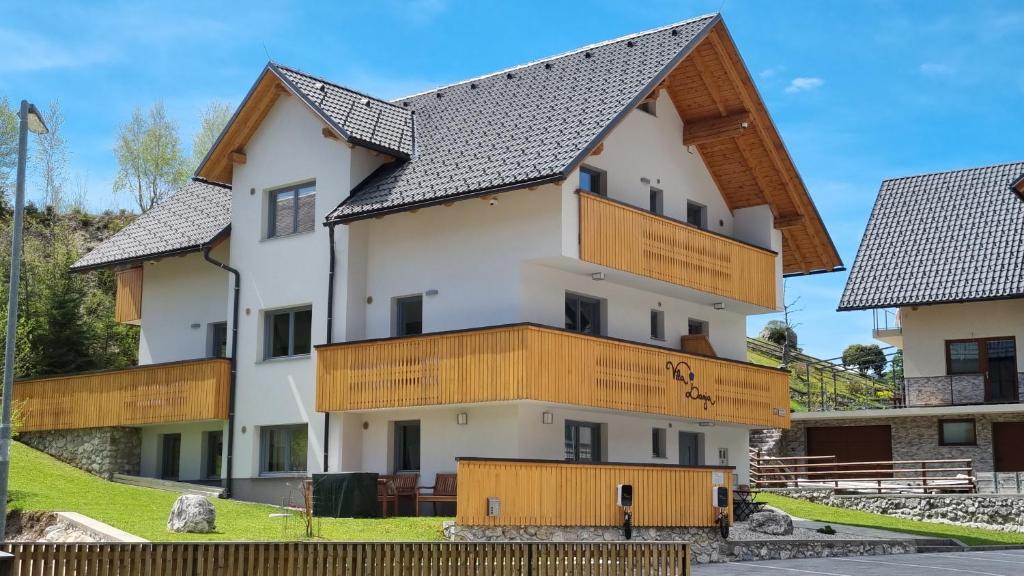 - un grand bâtiment blanc avec des balcons en bois dans l'établissement Apartments Vila Darja, à Bohinj