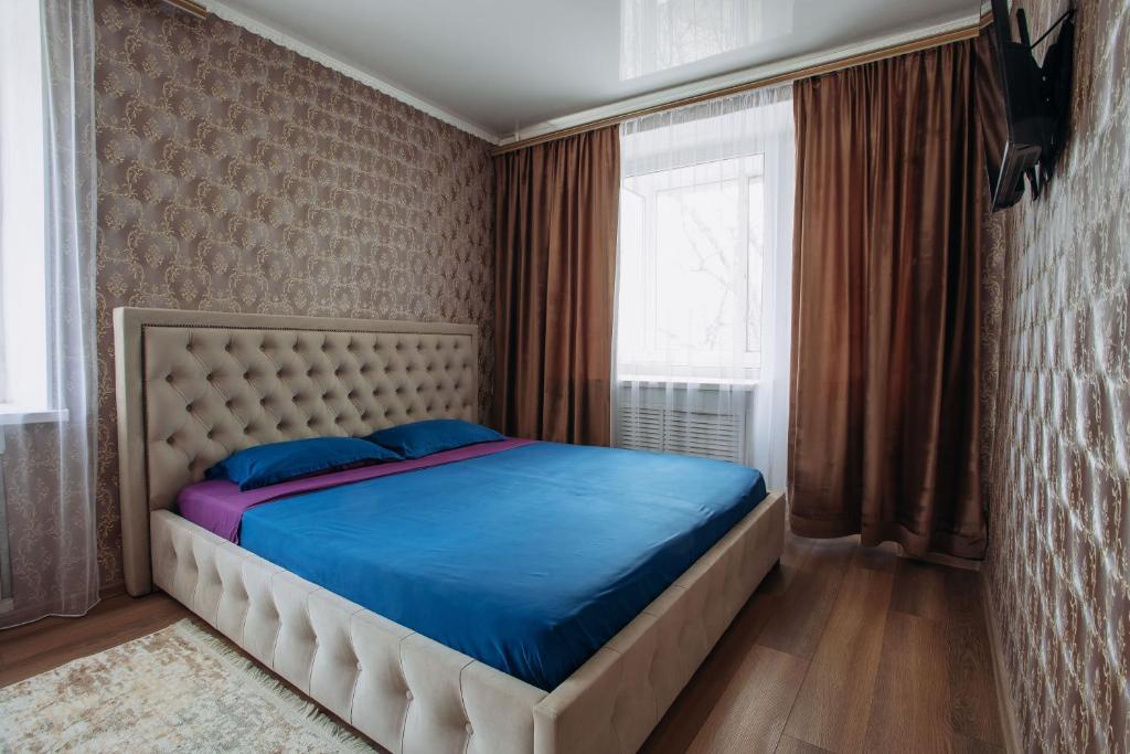 1 dormitorio con cama con sábanas azules y ventana en 1-комнатная квартира в центре на Аль-Фараби 93 en Kostanái