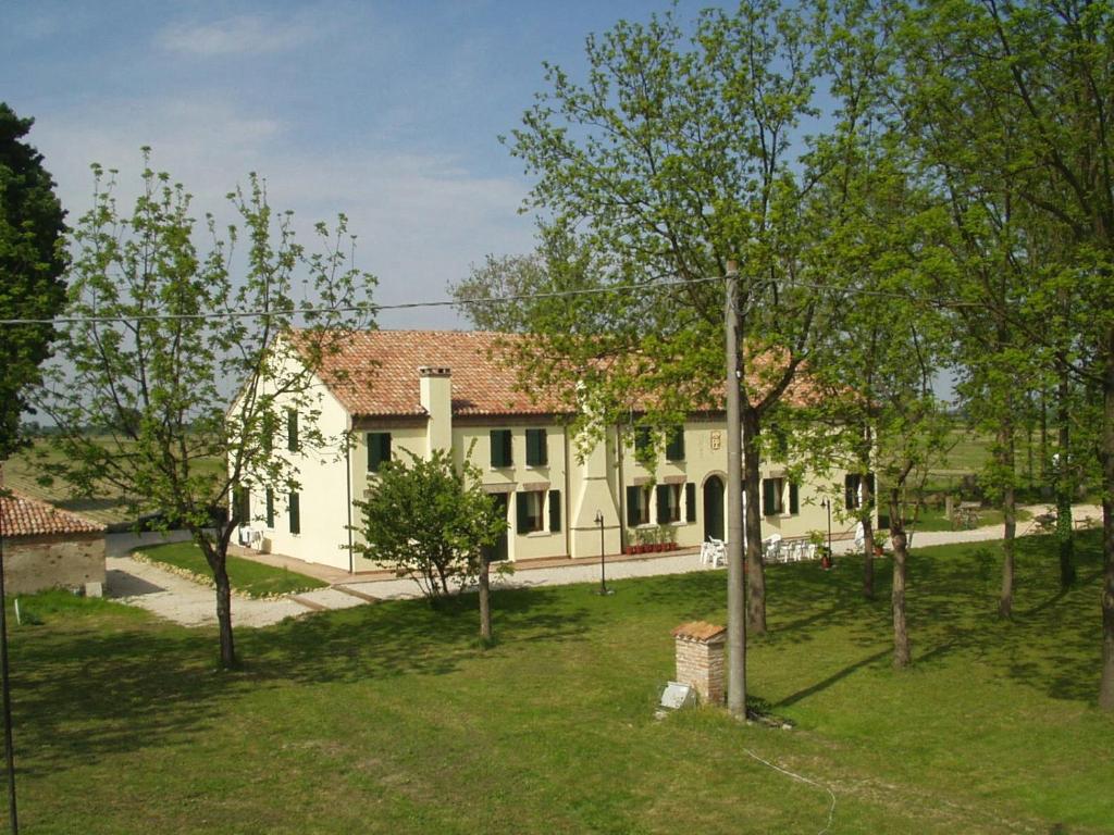 una casa bianca con degli alberi di fronte di Agriturismo Principe Pio a Crespino