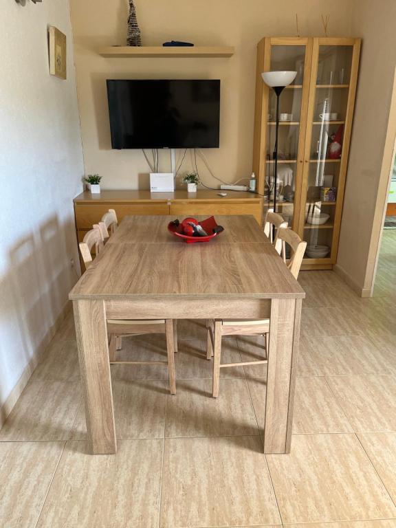 uma mesa de madeira com cadeiras e uma televisão num quarto em Apartamento Hifrensa em L'Hospitalet de l'Infant