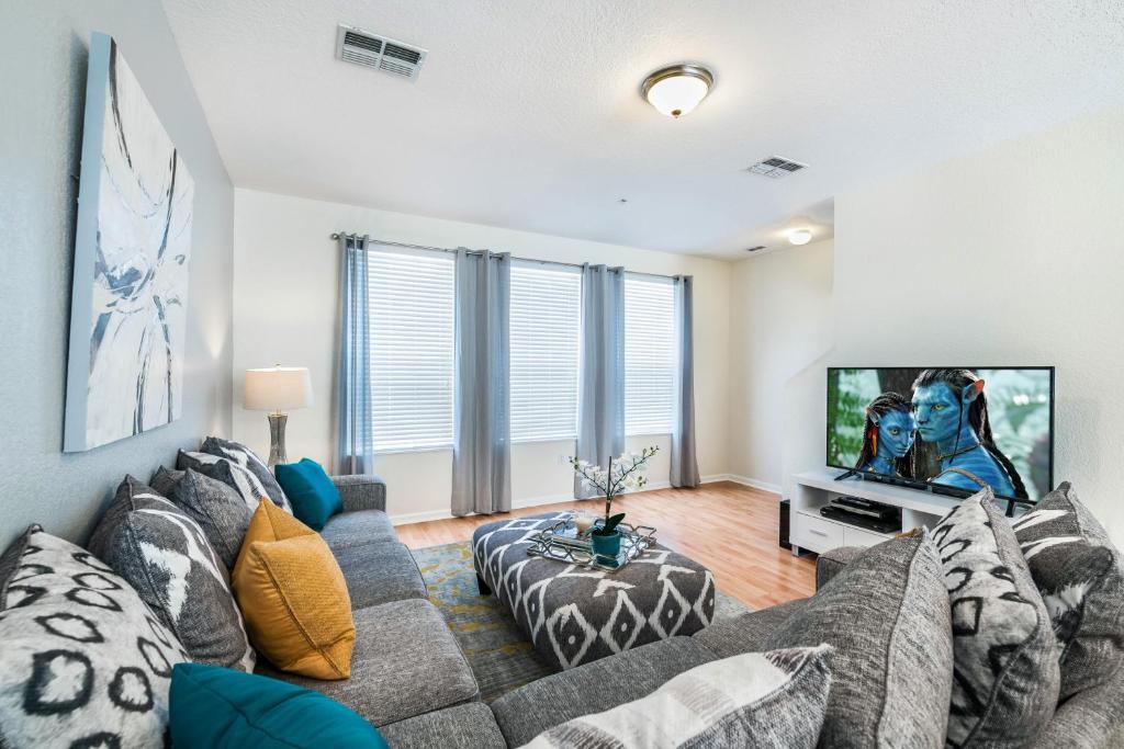 ein Wohnzimmer mit einem Sofa und einem Flachbild-TV in der Unterkunft Beautiful Newly Updated Townhome Sleeps 10 in Orlando