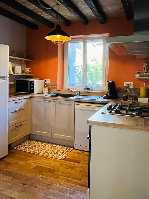 a kitchen with orange walls and a stove top oven at Le Georges V in Alzonne