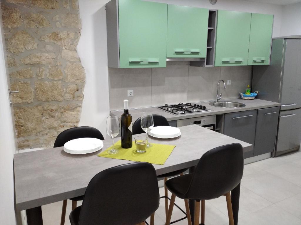 una cocina con una mesa con sillas y copas de vino en Apartman Lari, en Vižinada