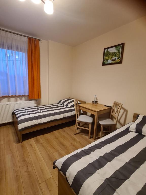 Cette chambre comprend deux lits, une table, une table et des chaises. dans l'établissement MARMI Noclegi, à Golczowice