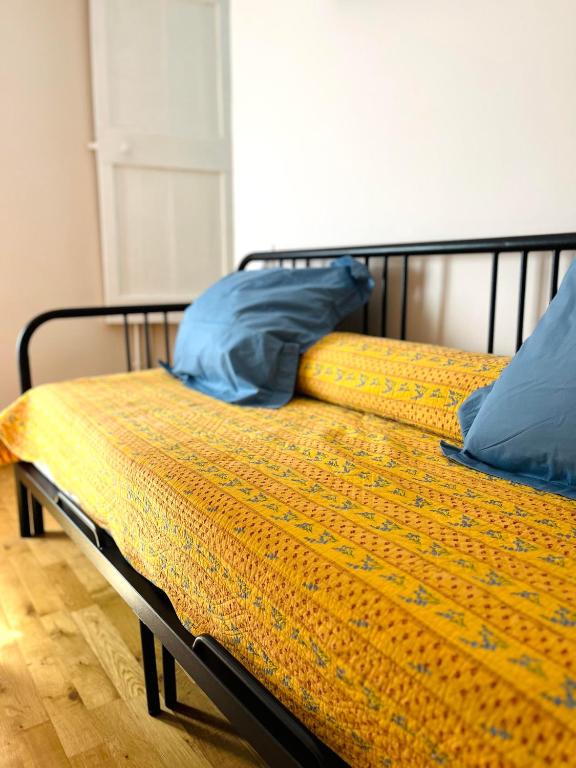 a bed with yellow sheets and blue pillows on it at Le Georges V in Alzonne
