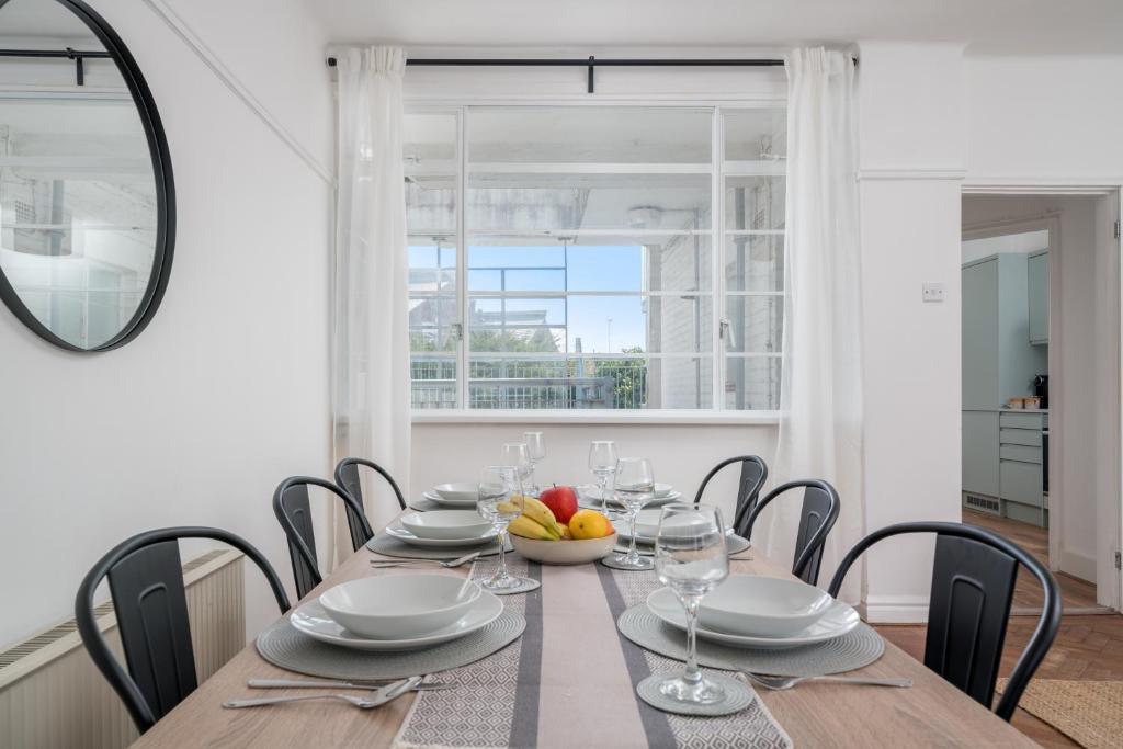 a dining room with a table and chairs and a window at Bright West Hampstead Retreat in London