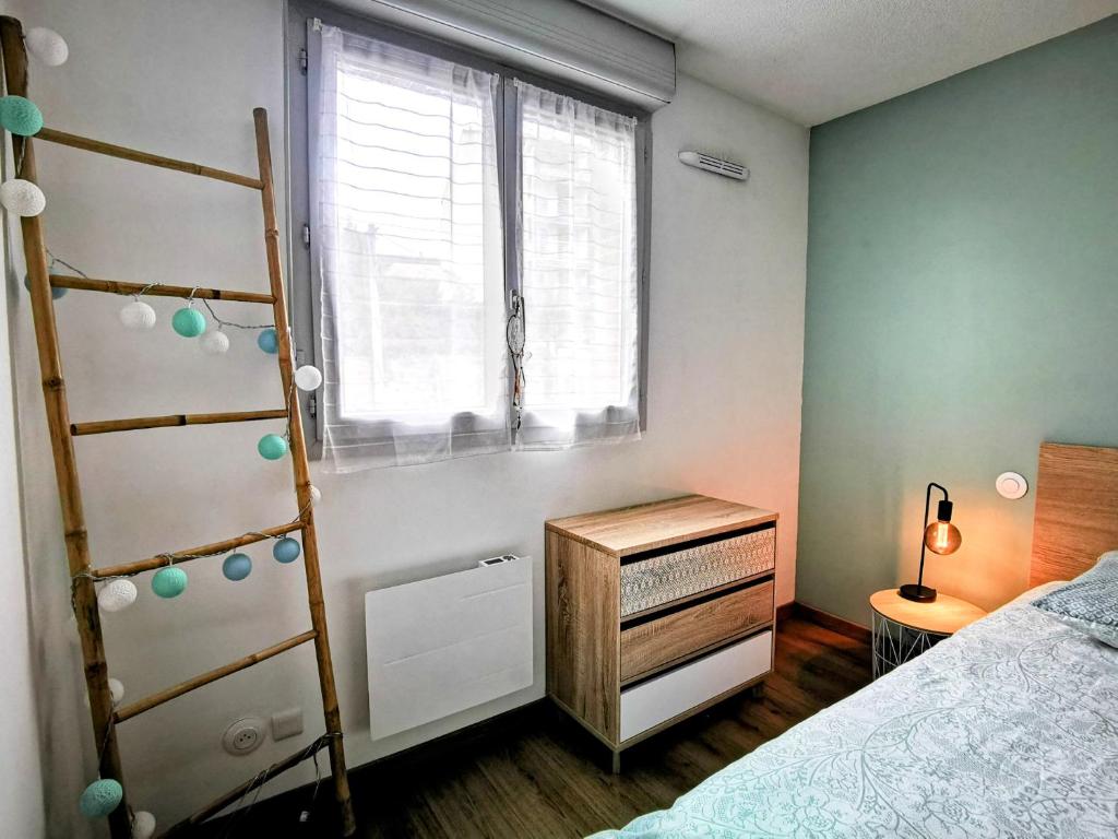 1 dormitorio con escalera, cama y ventana en Cocon Urbain - avec parking privé gratuit, en Toulouse