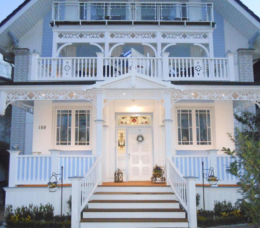 ein blau-weißes Haus mit einer Veranda und einer Treppe in der Unterkunft Haus Anholt in Timmendorfer Strand