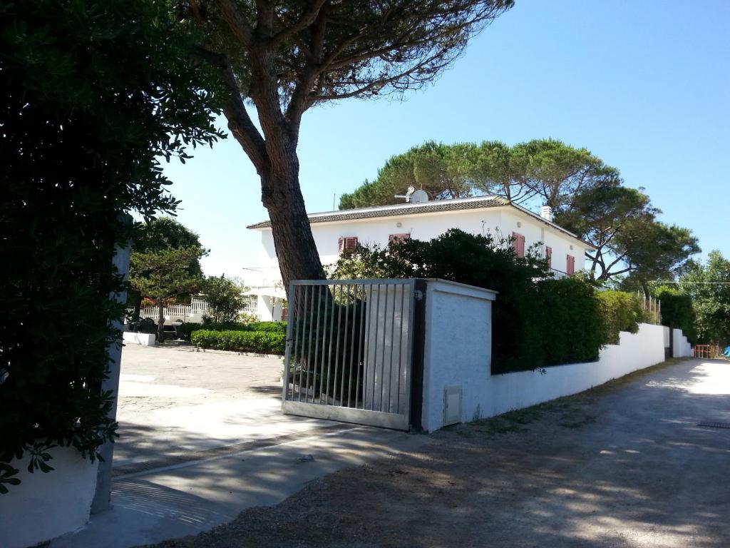 ミントゥルノにあるAppartamento in Villa Valentini, Fronte mare, Giardino e parcheggio privato, WIFI, dotato di tutti i confort, nel Golfo di Gaetaの門と木のある白い家