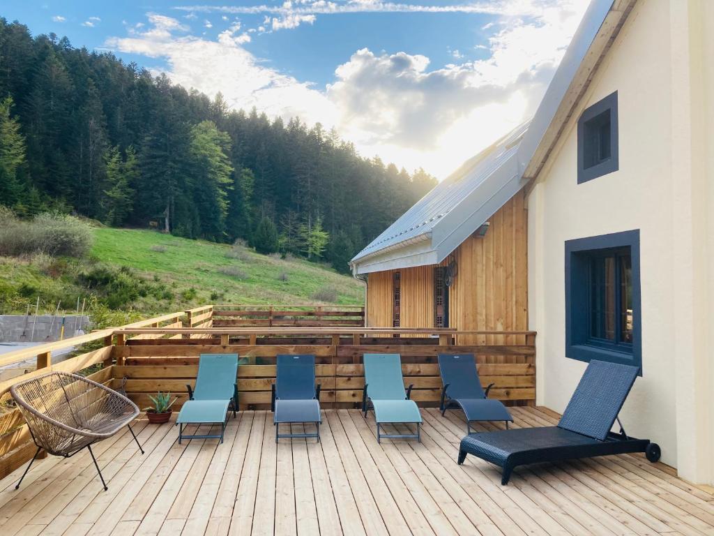 una terraza con sillas y una mesa en un edificio en Le Perchoir du Grand Valtin - Gîte 9 personnes - Altitude 830, en Ban-sur-Meurthe-Clefcy