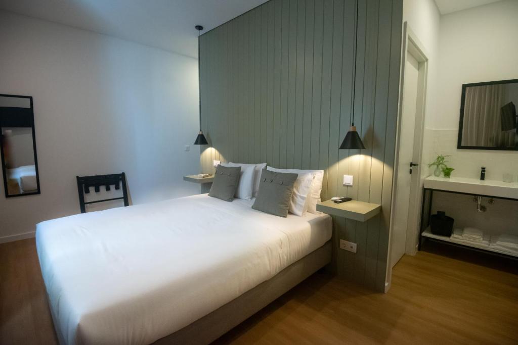 a bedroom with a large white bed and a mirror at Olive Boutique Guesthouse in Vila Franca do Campo