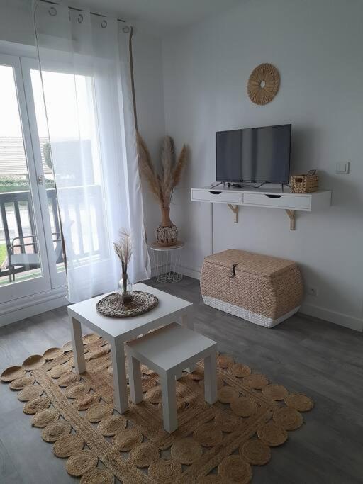 un salon avec une table et une télévision dans l'établissement Appartement T2 avec balcon refait à neuf, à Villers-sur-Mer