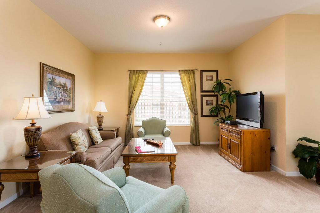 ein Wohnzimmer mit einem Sofa und einem TV in der Unterkunft Florida Palms in Orlando