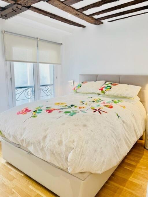 - un lit blanc orné de fleurs dans la chambre dans l&#39;établissement ENJOY PARIS, à Paris