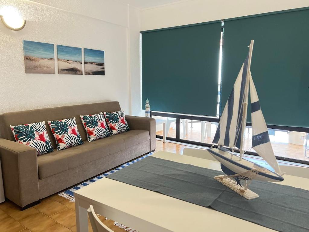 a living room with a couch and a sail boat on a table at Encantador apartamento com piscina in Costa da Caparica