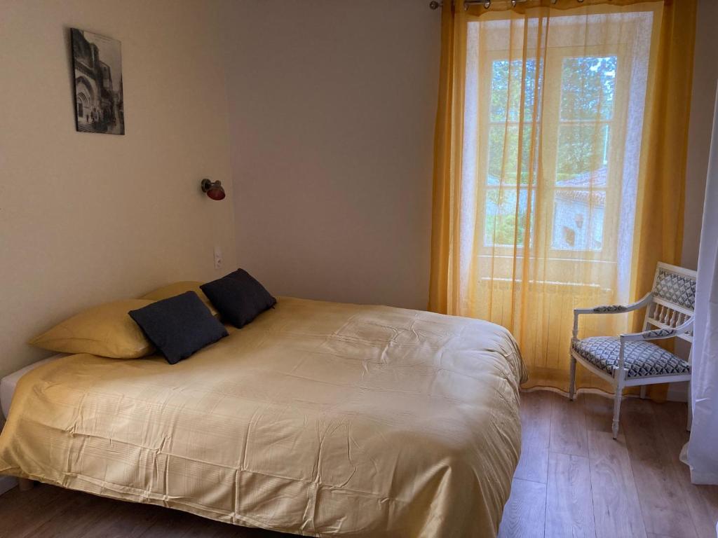 een bed in een slaapkamer met een raam en een stoel bij La maison du pech in Monteils