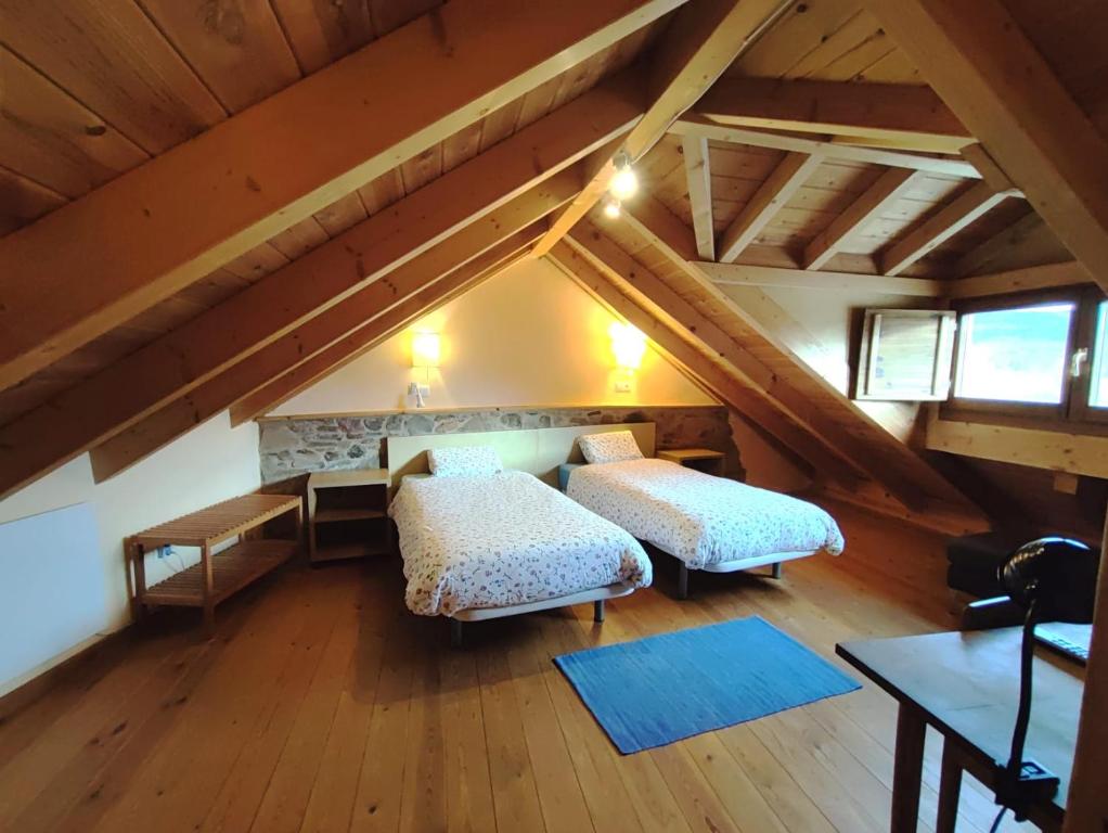 Cette chambre mansardée comprend deux lits et une cheminée. dans l'établissement La Gándara Casa Rural, à San Justo de Cabanillas