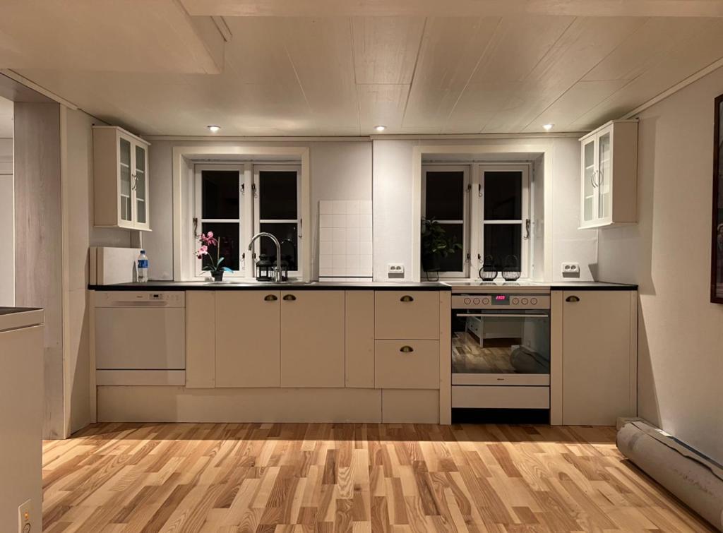 cocina con armarios blancos y suelo de madera en Cory & Torfinn House, en Sørvágur