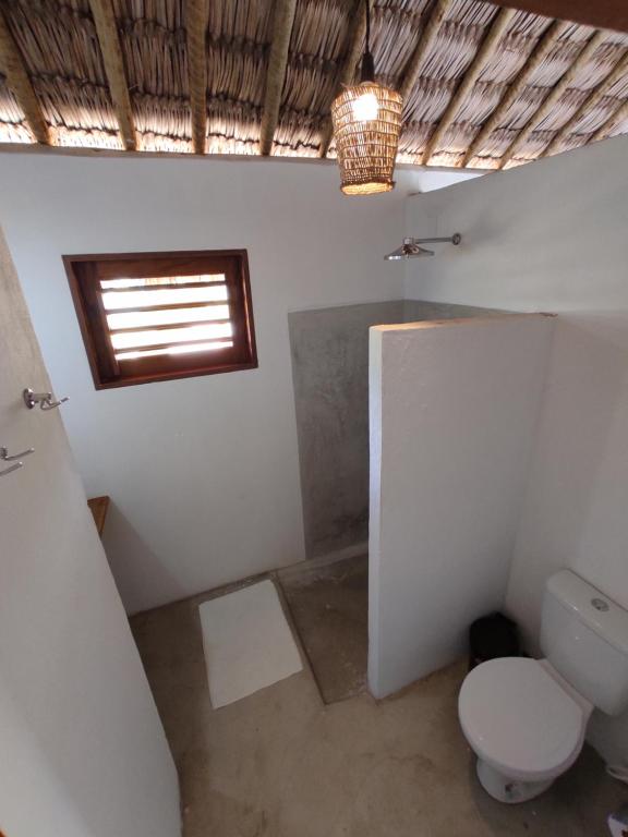 a bathroom with a toilet and a window at Pitico Chalé - Icaraí Kite Village in Icaraí