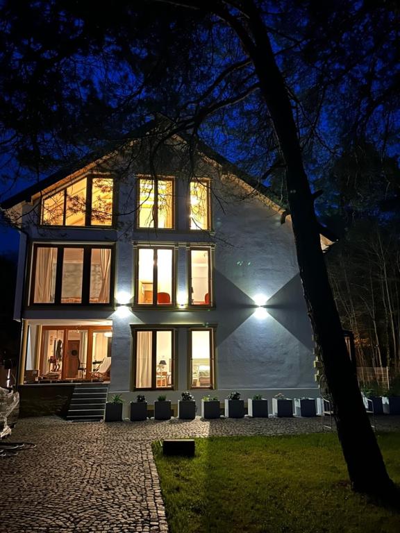 a large white house at night with lights at Leśna Residence & SPA in Pisz