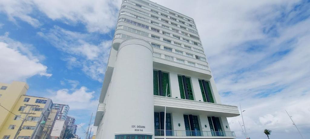 a tall white building with green windows at COBAR0108 - Edifício Oceania in Salvador