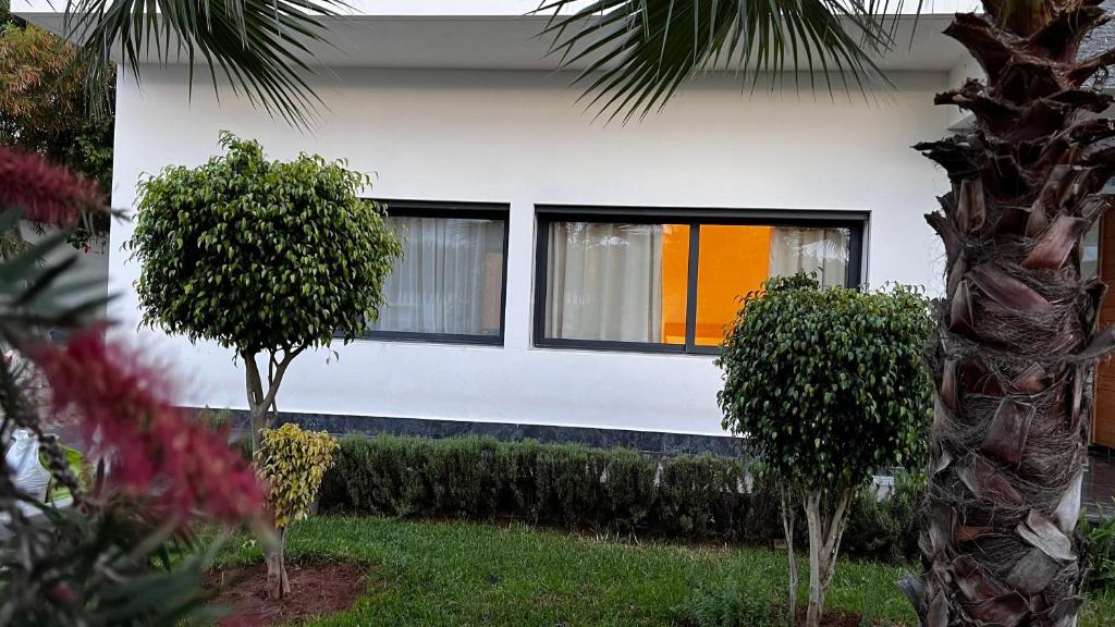 une maison blanche avec des fenêtres et des buissons devant elle dans l'établissement Cozy Appartement in a Villa close to Mahaj Riad Rabat, à Rabat