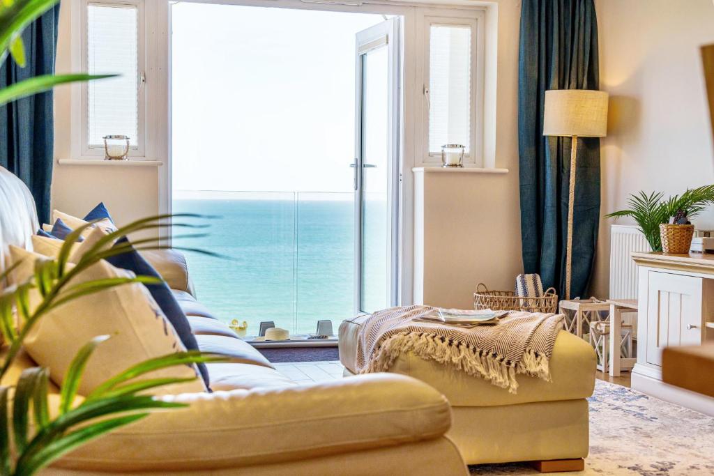 a living room with a couch and a large window at Carbis Bay - Luxury 3 Bed Penthouse Apartment with Sea Views Parking Sauna Balcony in Carbis Bay