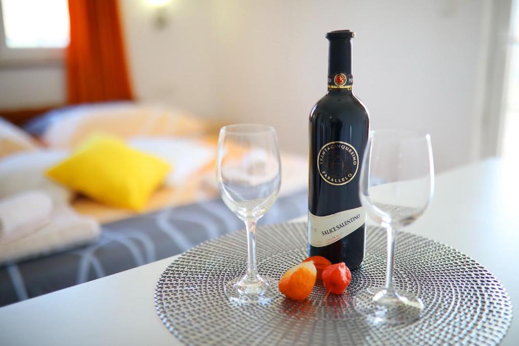 una botella de vino y dos copas de vino en una mesa en Rooms & Studio apartmani Flower, en Bibinje