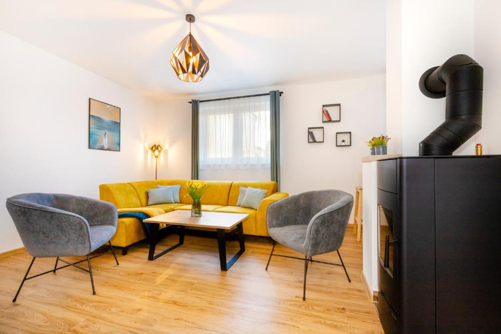 Dům u Mlejna : غرفة معيشة مع أريكة صفراء وكراسي