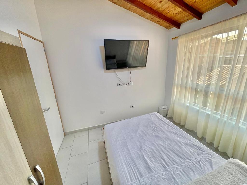 ein Schlafzimmer mit einem Bett und einem TV an der Wand in der Unterkunft Apto para estrenar en San Antonio de Pereira in Rionegro