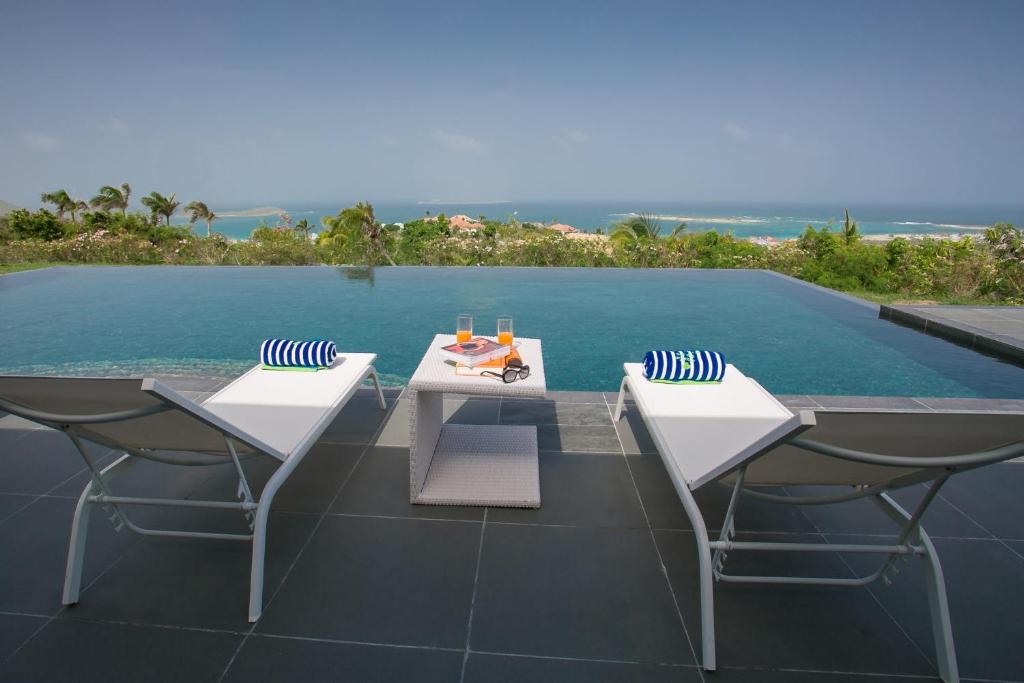 two chairs and a table next to a swimming pool at Villa Monte Verde in Orient Bay