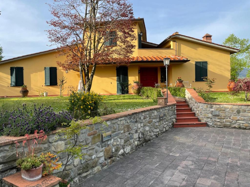 a yellow house with a stone wall at Villa Elisa in Scarperia