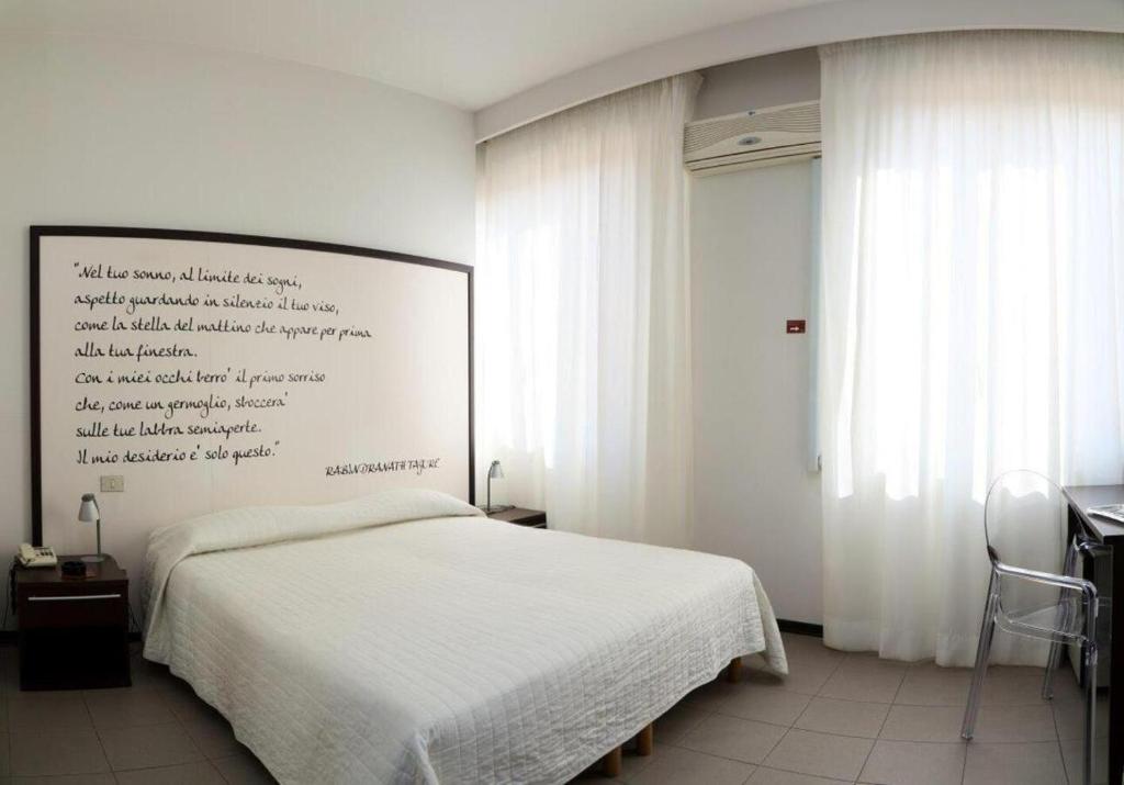 - une chambre avec un lit blanc et un mur blanc dans l'établissement Hotel Solarium, à Civitanova Marche