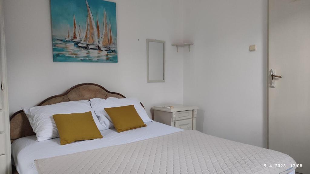 a bedroom with a white bed with two yellow pillows at Pejovic Guest House in Sutomore