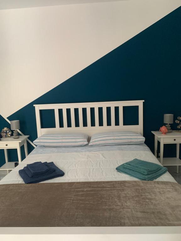 a bedroom with a white bed with a blue wall at Torrevarata vacanze in Santa Teresa di Riva
