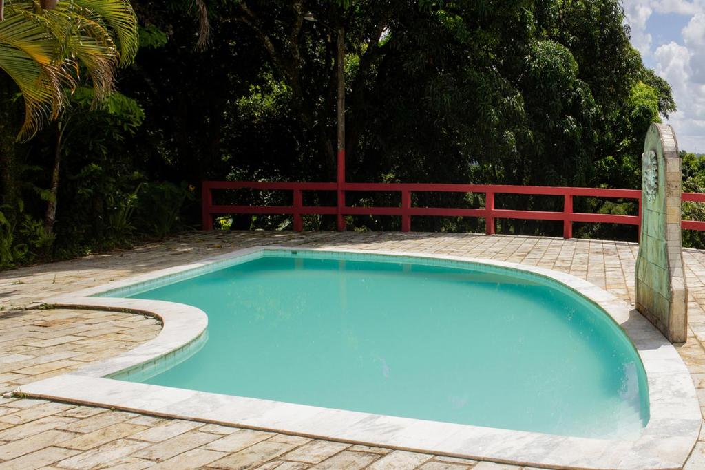 São Lourenço da Mata的住宿－Chacara c piscina e lazer Sao Lourenco da Mata PE，蓝色的游泳池四周环绕着红色的围栏