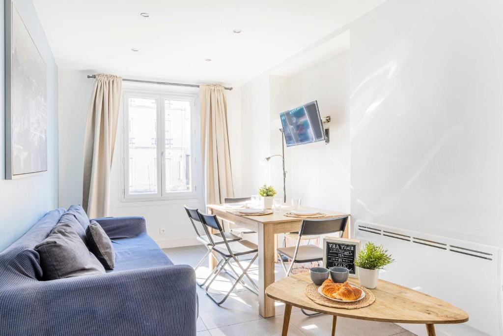 uma sala de estar com um sofá azul e uma mesa em Bright apartment - 2BR - Place de la BastilleSt Antoine em Paris