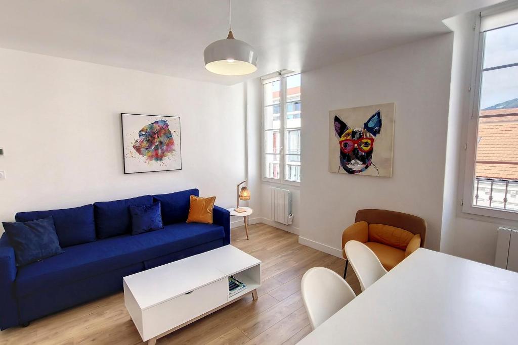 een woonkamer met een blauwe bank en een tafel bij HENRI CAMILLE REAL ESTATE - Bambou- One bedroom center in Cannes