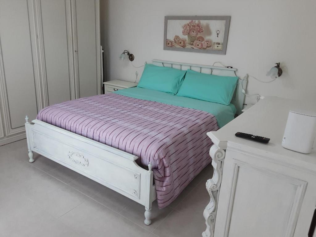 ein weißes Schlafzimmer mit einem Bett mit einer lila Decke in der Unterkunft La casetta nella Tuscia in Viterbo