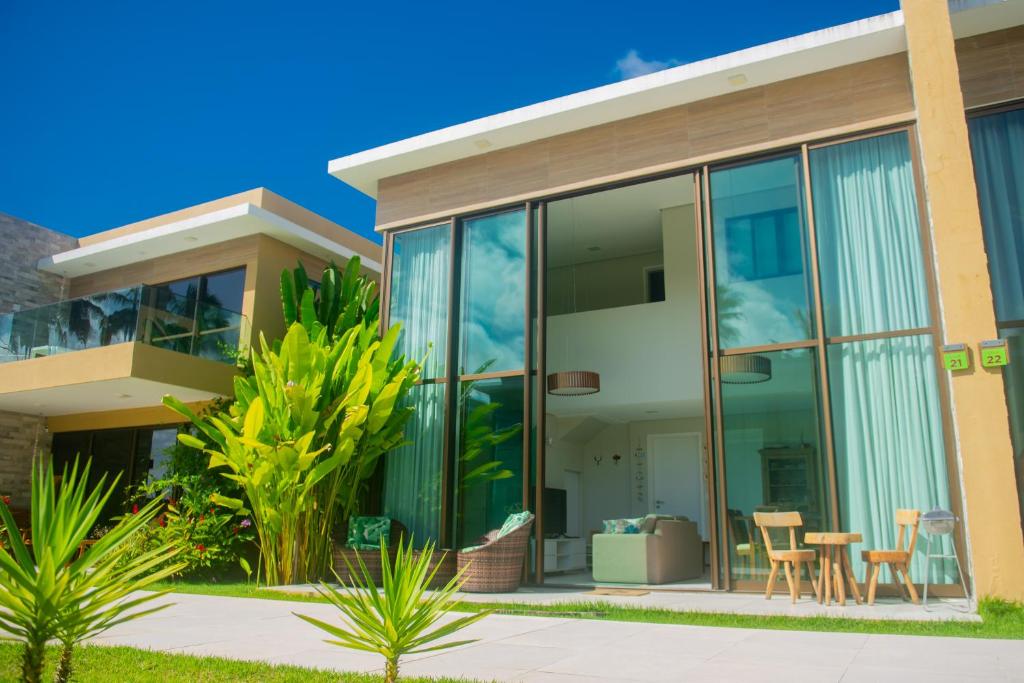 a house with large glass windows and a patio at Na Morada dos Milagres, condomínio Morada do Toque in São Miguel dos Milagres