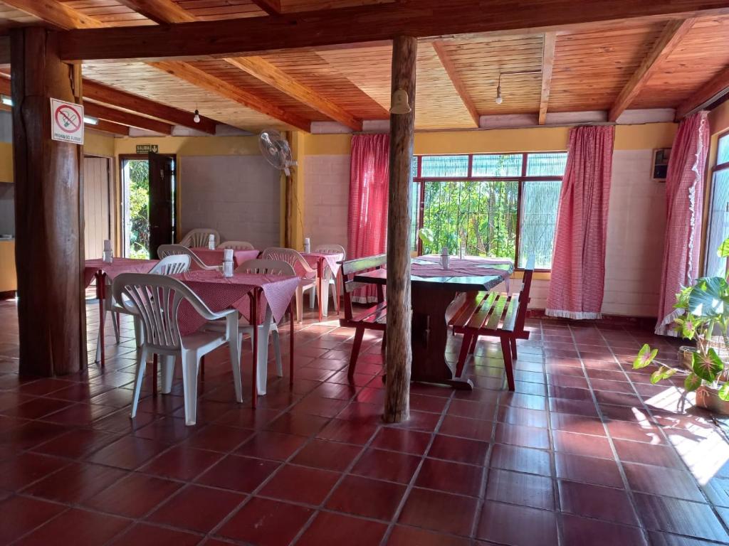 una sala da pranzo con tavoli, sedie e finestre di La casona a Puerto Iguazú