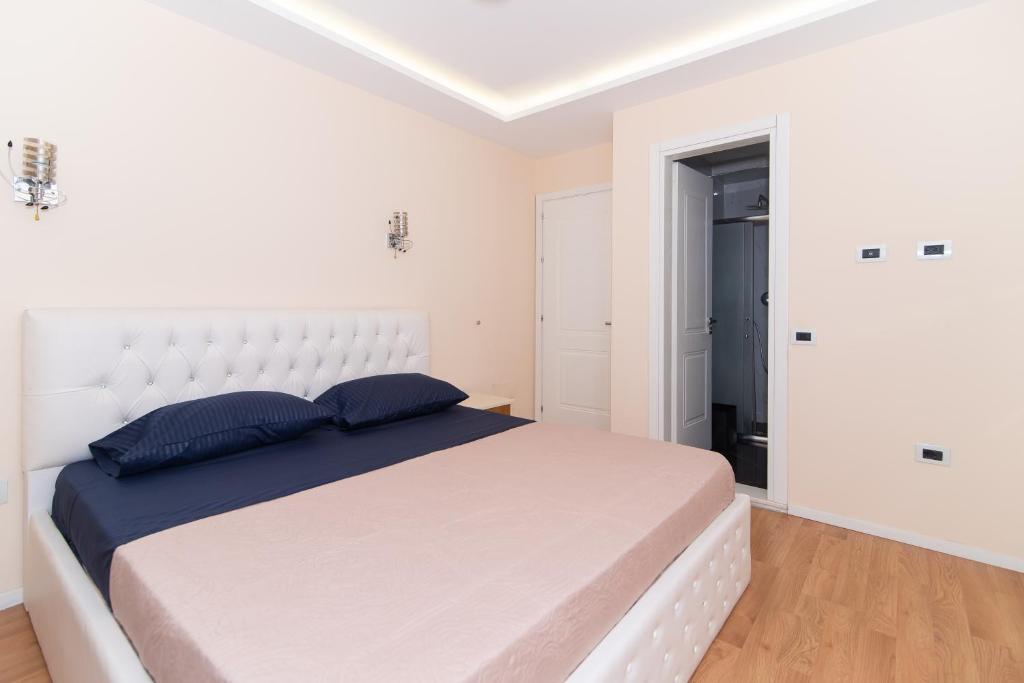 ein weißes Schlafzimmer mit einem großen weißen Bett mit blauen Kissen in der Unterkunft Tirana Central Exclusive in Tirana
