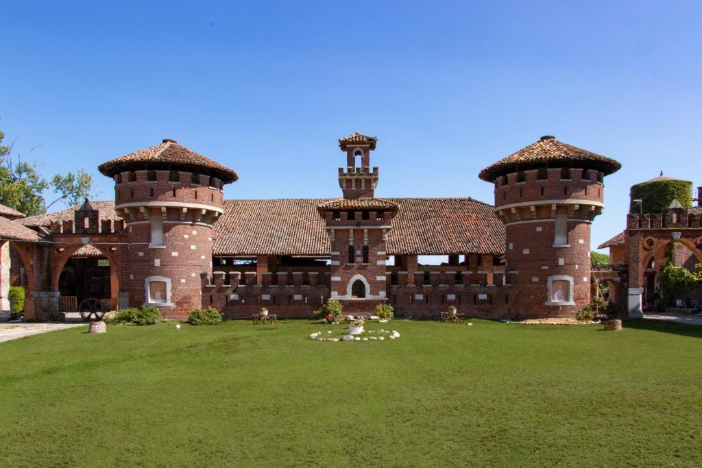 un grand bâtiment en briques avec deux tours sur une pelouse dans l'établissement Mahthildis Agriturismo B&B, à Vermezzo